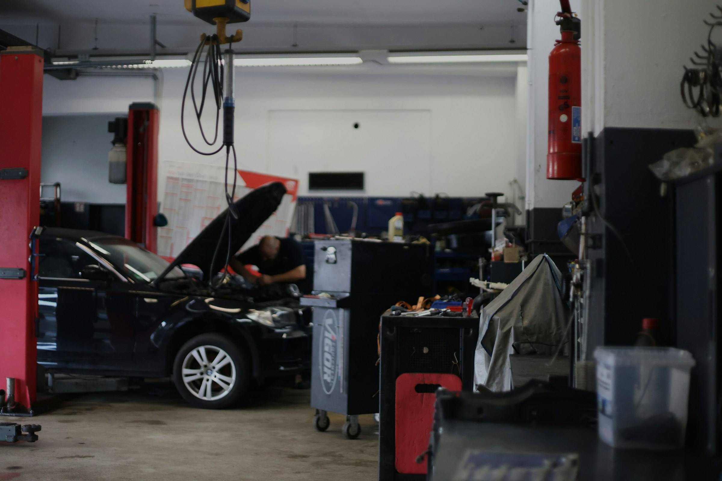 Mechaniker arbeitet im Motorraum eines Fahrzeugs in einer Werkstatt